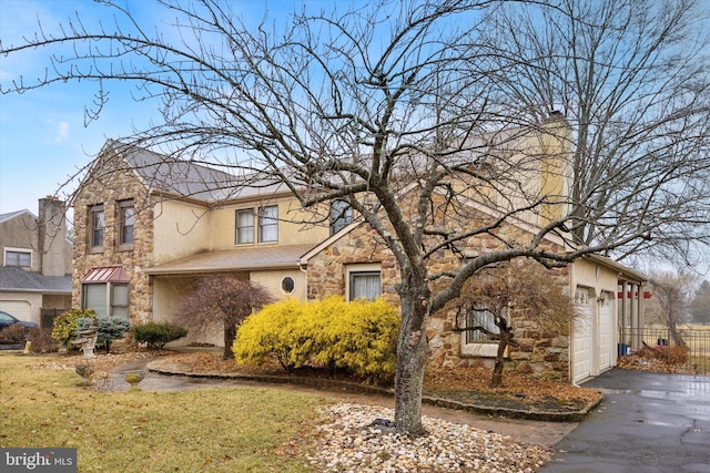 traditional home with stone siding, driveway, and stucco siding