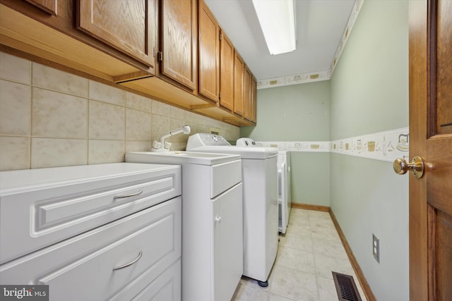 laundry room featuring cabinet space, light tile patterned floors, baseboards, visible vents, and washing machine and clothes dryer