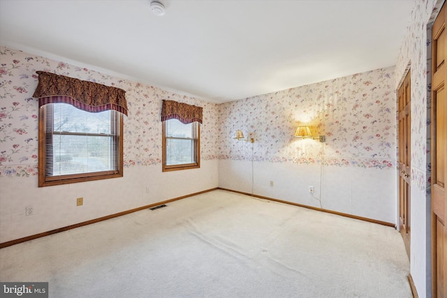 spare room featuring wallpapered walls, baseboards, visible vents, and carpet flooring