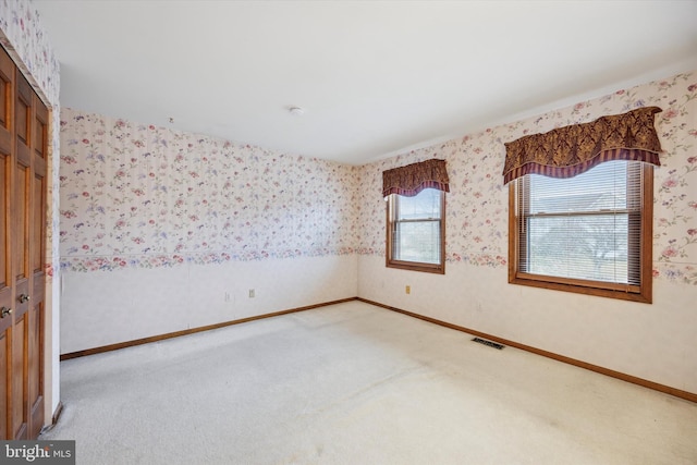 unfurnished room featuring light carpet, baseboards, visible vents, and wallpapered walls