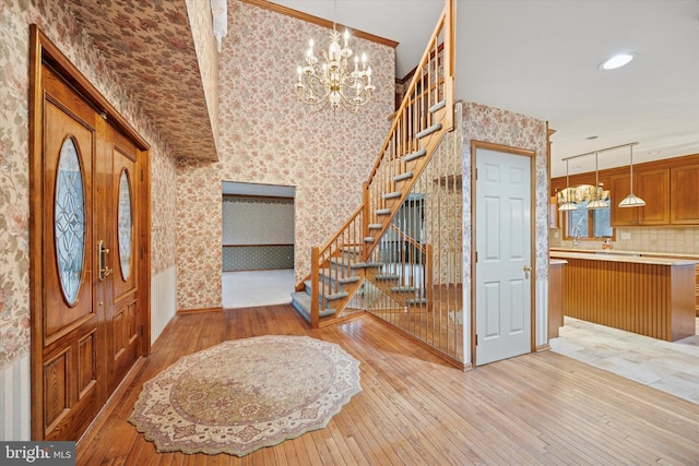 foyer entrance featuring a chandelier, recessed lighting, light wood-style floors, stairs, and wallpapered walls