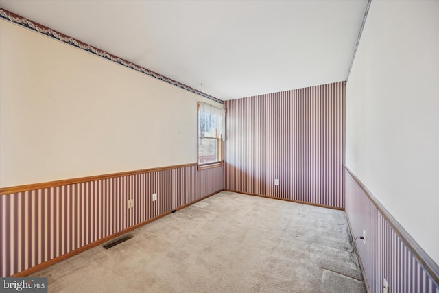 unfurnished room with carpet, wainscoting, and visible vents