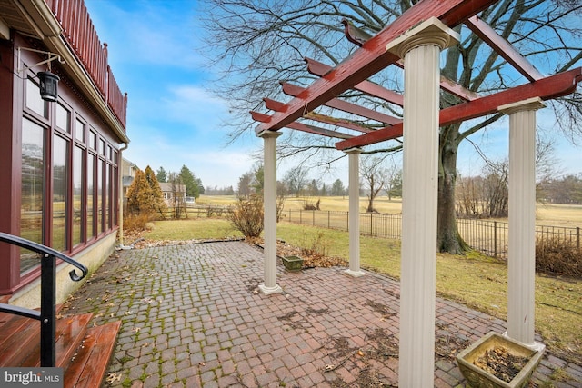 view of patio featuring a rural view, fence, and a pergola