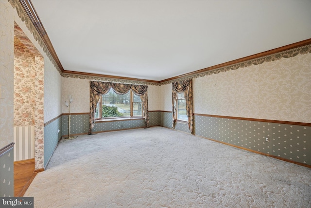 empty room featuring carpet, crown molding, and wallpapered walls