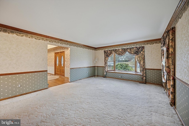 carpeted empty room featuring crown molding and wallpapered walls