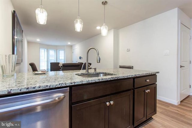 kitchen featuring light stone counters, light wood-style flooring, a sink, dark brown cabinets, and dishwasher