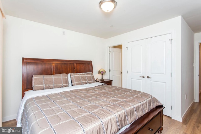 bedroom with light wood-type flooring, baseboards, and a closet