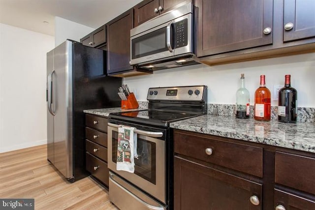 kitchen with baseboards, light wood-style flooring, appliances with stainless steel finishes, light stone countertops, and dark brown cabinets