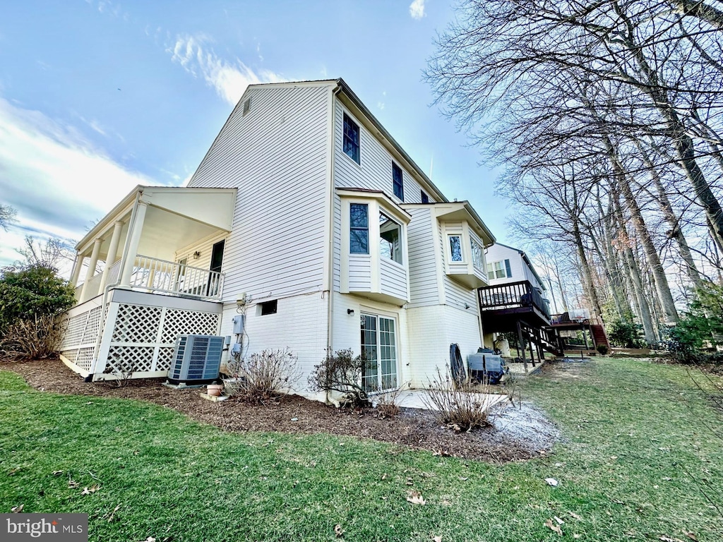 back of property featuring central air condition unit, a deck, a patio area, and a yard