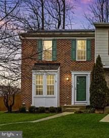 view of front of home featuring entry steps, a front lawn, and brick siding