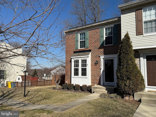 view of front of property with entry steps, brick siding, a front yard, and fence