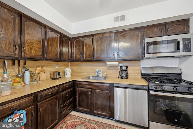 kitchen featuring appliances with stainless steel finishes, sink, dark brown cabinets, and tasteful backsplash