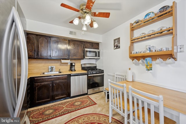 kitchen featuring stainless steel appliances, sink, backsplash, dark brown cabinets, and ceiling fan