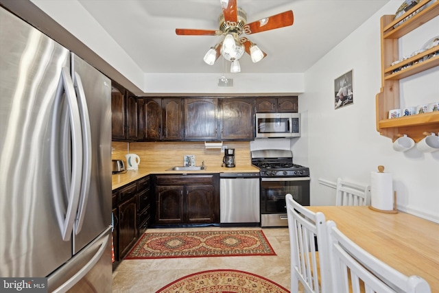 kitchen featuring tasteful backsplash, stainless steel appliances, dark brown cabinetry, ceiling fan, and sink