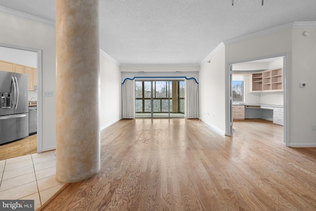 unfurnished living room featuring crown molding, built in desk, and light wood-style floors