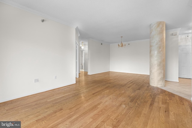 empty room with a chandelier, light wood-type flooring, and crown molding