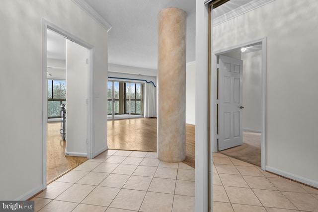 corridor featuring ornamental molding, light colored carpet, light tile patterned flooring, and baseboards