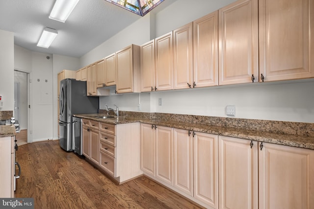 kitchen featuring stone counters, dark wood-type flooring, a sink, and a textured ceiling