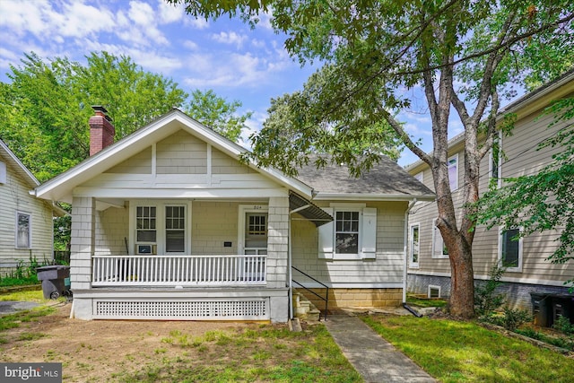 bungalow-style home with a porch, a front lawn, and a shingled roof