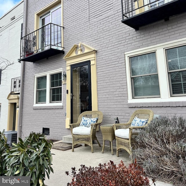 entrance to property featuring central AC, brick siding, crawl space, and a patio