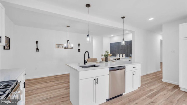 kitchen featuring stainless steel appliances, a sink, white cabinets, light countertops, and decorative light fixtures