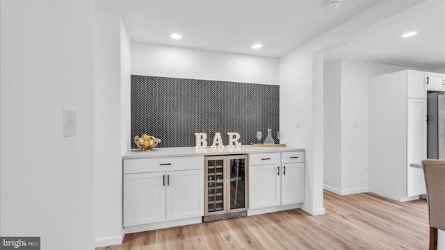 bar with a dry bar, beverage cooler, baseboards, light wood-style flooring, and recessed lighting