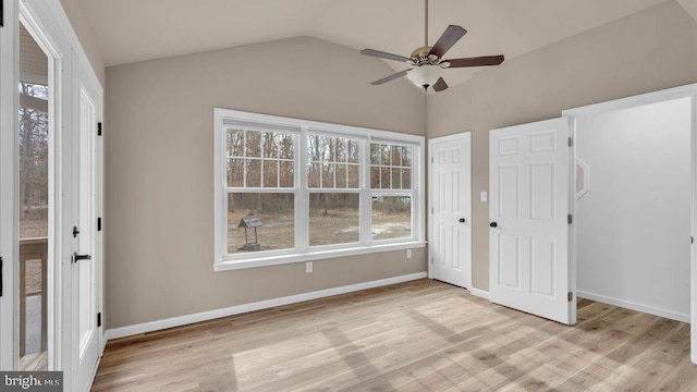 unfurnished bedroom featuring light wood finished floors, baseboards, and vaulted ceiling