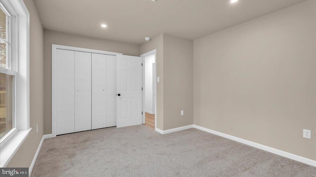 unfurnished bedroom with recessed lighting, a closet, light carpet, and baseboards