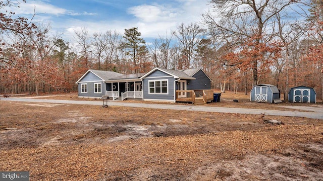 view of front of house featuring a storage shed, a porch, and an outbuilding