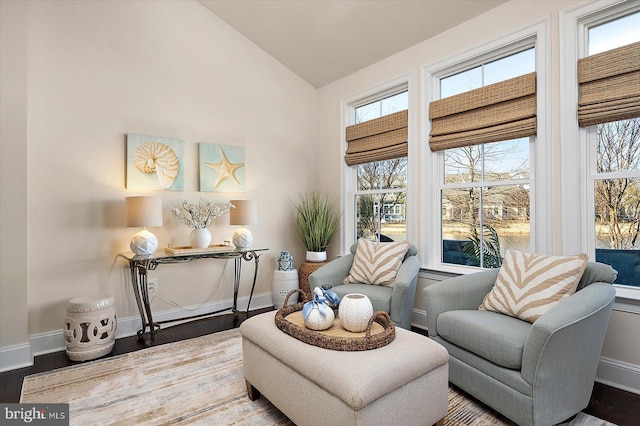 living area with vaulted ceiling, baseboards, and wood finished floors