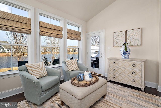 living area with a water view, baseboards, vaulted ceiling, and wood finished floors