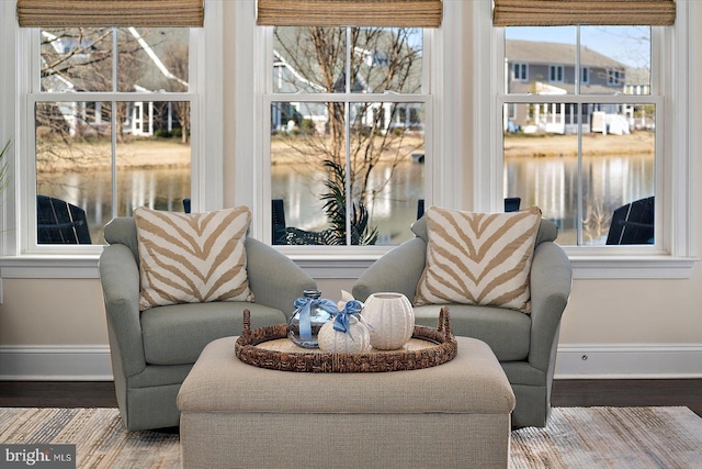 living area with a water view, baseboards, and wood finished floors