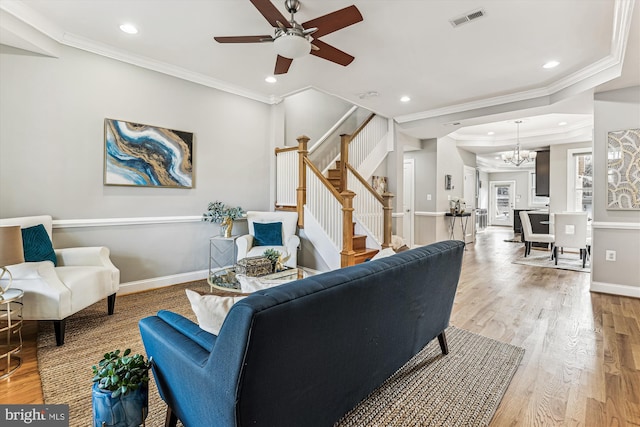 living area featuring light wood-style flooring, visible vents, crown molding, and stairway