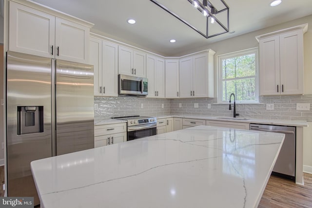 kitchen featuring recessed lighting, a sink, light stone counters, and appliances with stainless steel finishes