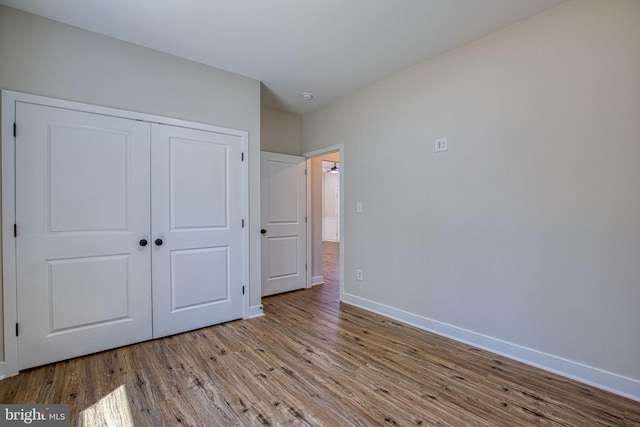 unfurnished bedroom with a closet, baseboards, and wood finished floors