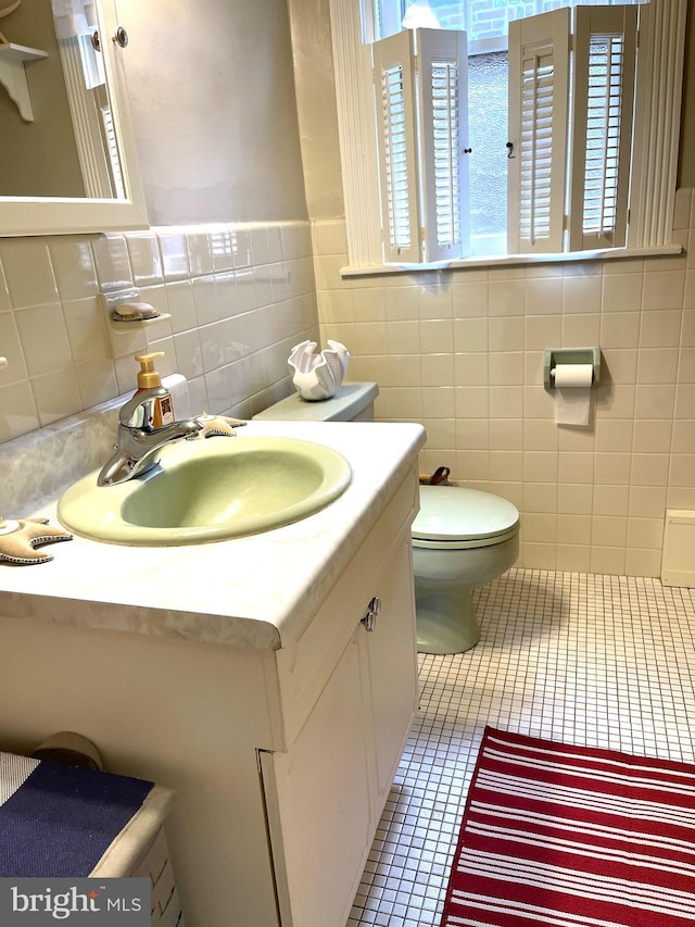 bathroom featuring tile walls, vanity, tile patterned flooring, and toilet