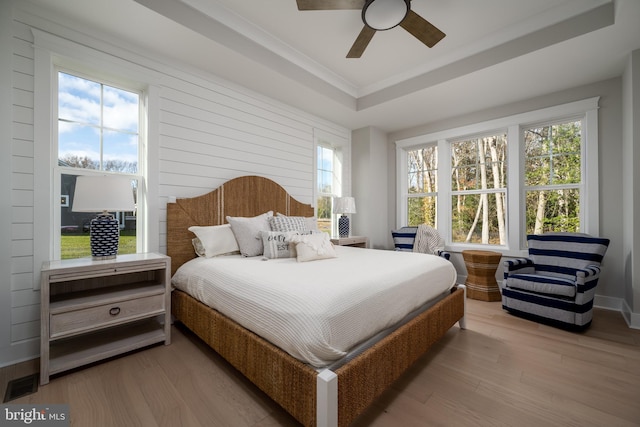 bedroom with a tray ceiling, ornamental molding, hardwood / wood-style floors, and ceiling fan