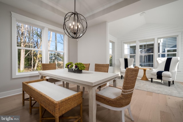 dining room with a chandelier, a raised ceiling, vaulted ceiling, and hardwood / wood-style floors