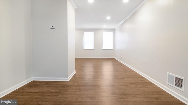 spare room with baseboards, visible vents, dark wood finished floors, and crown molding