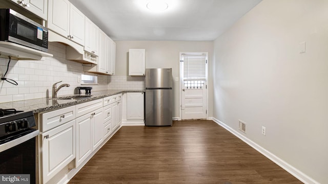 kitchen featuring white cabinets, decorative backsplash, appliances with stainless steel finishes, dark wood-style flooring, and stone counters