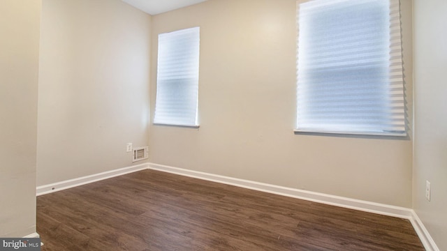 unfurnished room featuring visible vents, baseboards, and dark wood finished floors