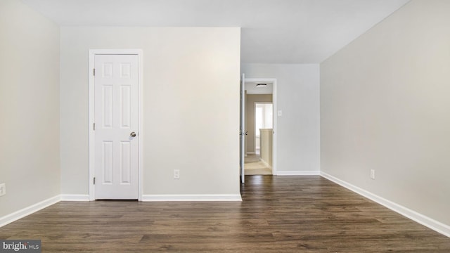 unfurnished bedroom with baseboards and dark wood-type flooring