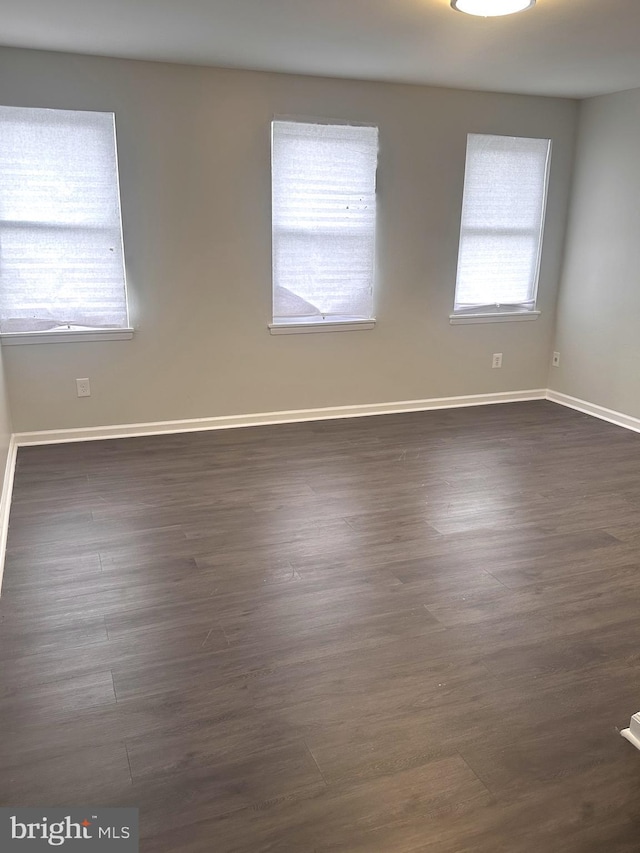 empty room featuring baseboards and dark wood-style flooring