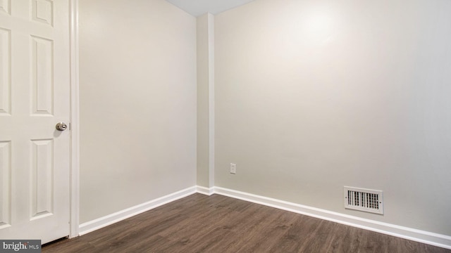 empty room with baseboards, visible vents, and dark wood finished floors