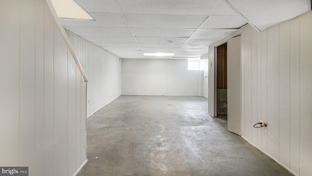 below grade area featuring wooden walls and a drop ceiling