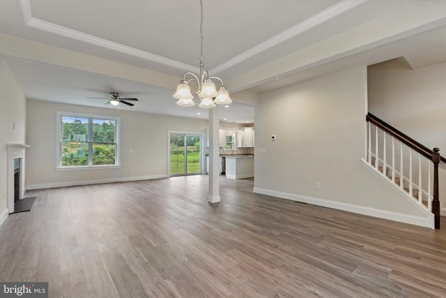 unfurnished living room with stairs, a tray ceiling, a fireplace, and baseboards