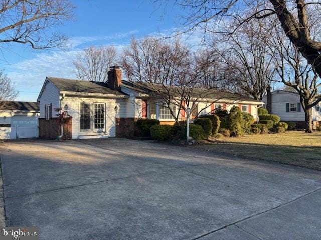 ranch-style home with a chimney and concrete driveway