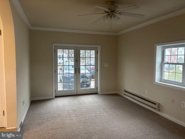 carpeted spare room featuring a baseboard radiator, baseboards, crown molding, and french doors