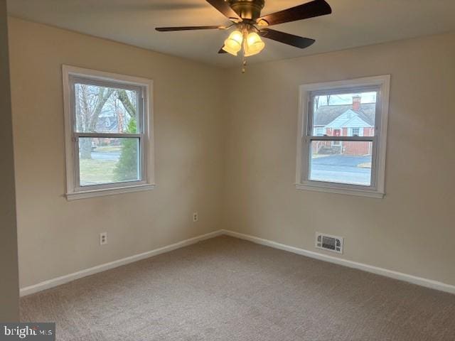 unfurnished room with carpet floors, visible vents, baseboards, and a ceiling fan