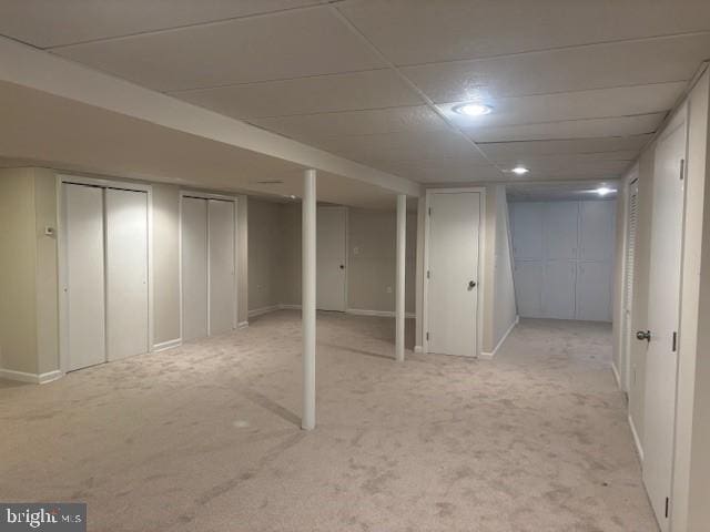 finished below grade area with a paneled ceiling and light colored carpet